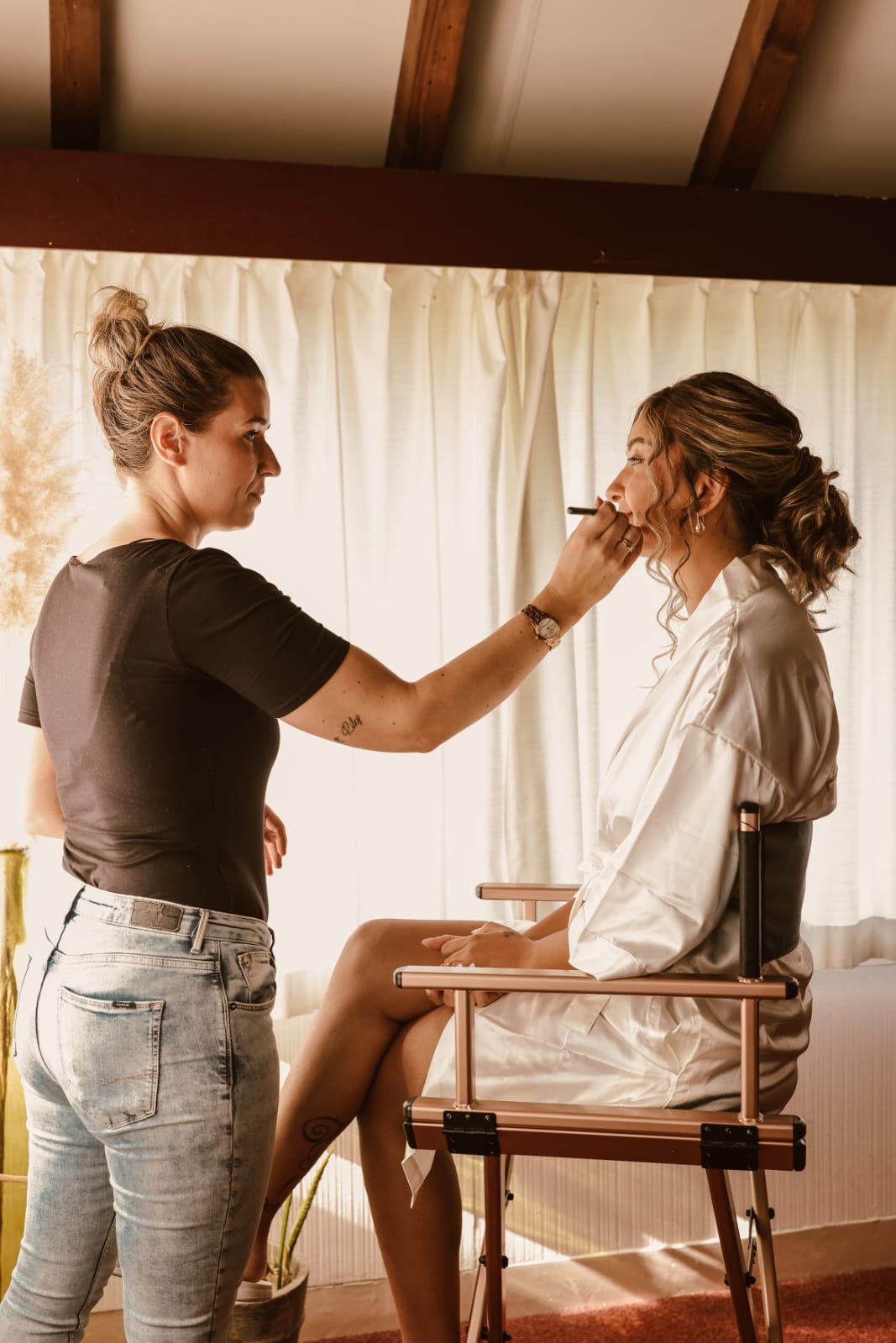 Felicia Tiebosch brengt make-up aan bij een bruid in een witte satijnen ochtendjas